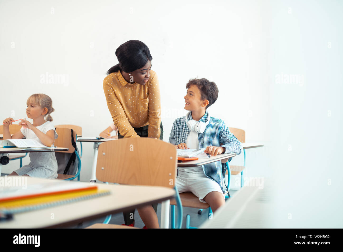 Dark-haired boy smiling while talking to his teacher Stock Photo