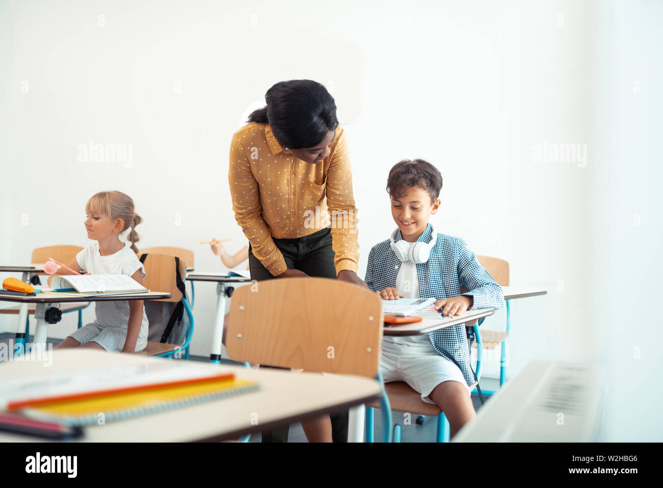 Dark-haired boy smiling while speaking with teacher Stock Photo