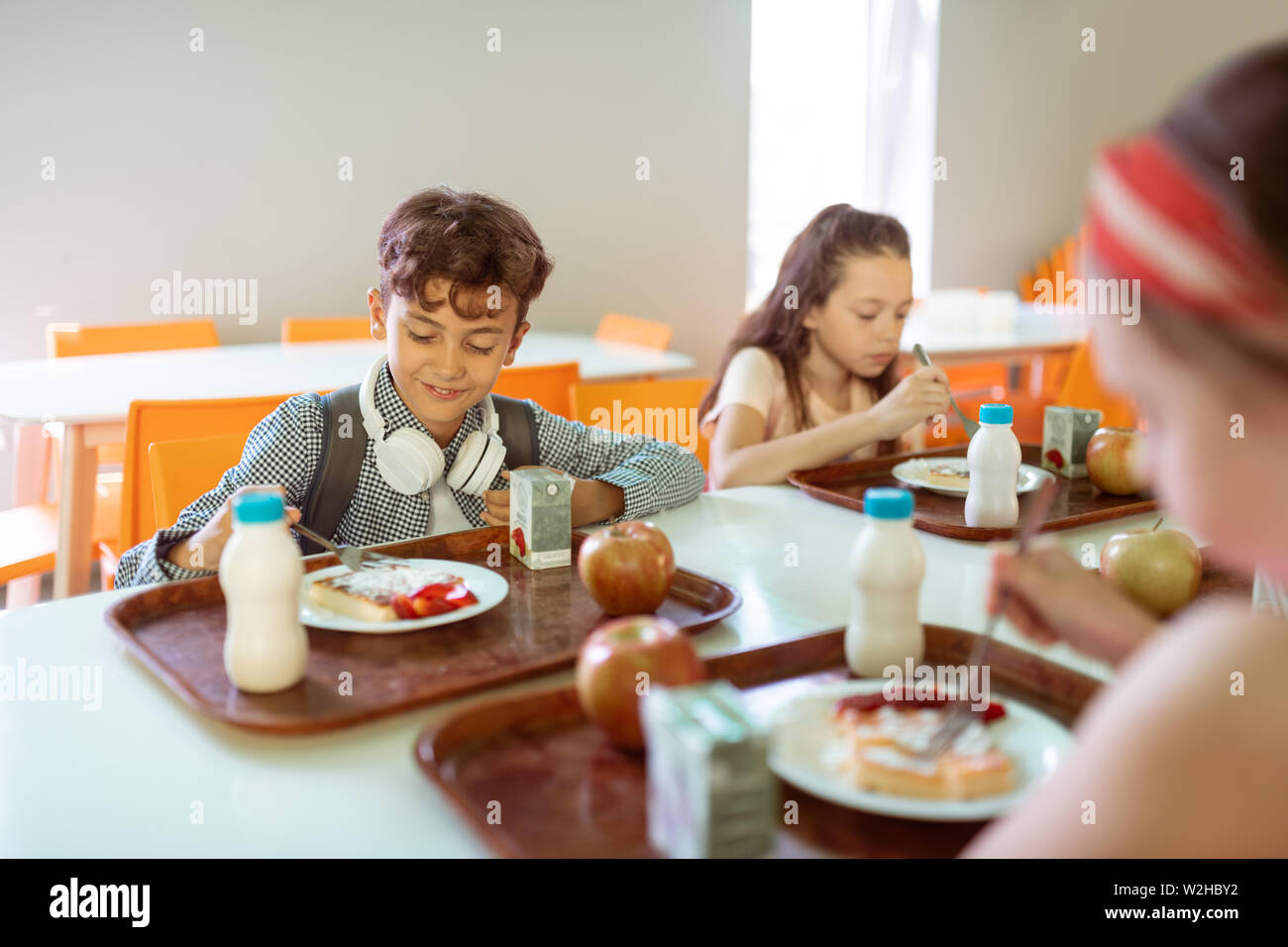 A group of cheerful small school kids in canteen, eating lunch. Stock Photo  by ©halfpoint 298162064