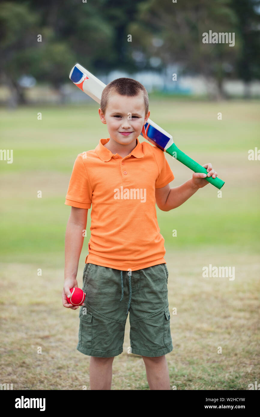 A portrait shot of a young caucasian boy wearing casual clothing, he is holding a cricket bat and ball and he is looking at the camera. Stock Photo