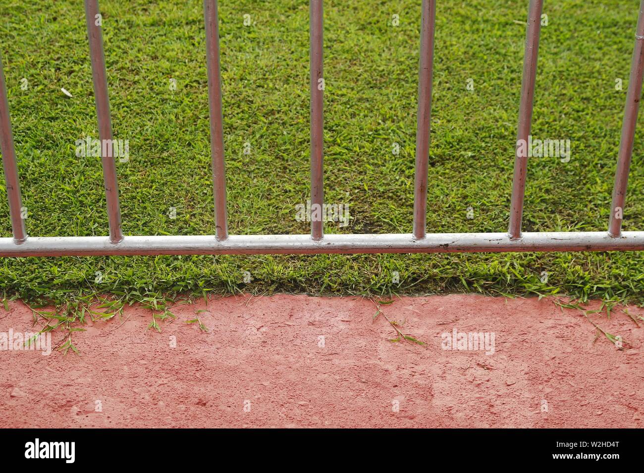 Photo of a steel fence or barricade and a green grass field Stock Photo