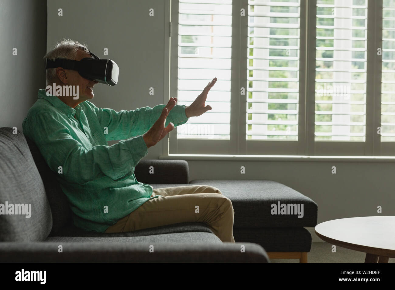 Active senior man using virtual reality headset in living room Stock Photo