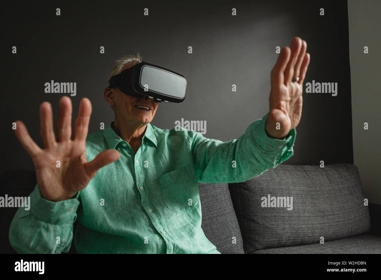 Active senior man using virtual reality headset in living room Stock Photo