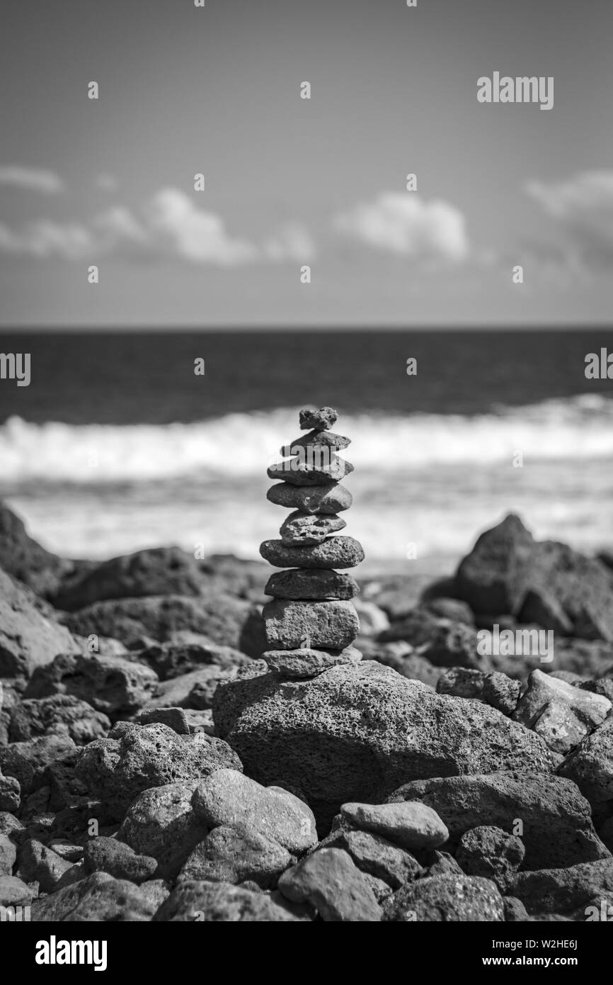 Pile of rocks stacked up on each other in perfect balance at the rocky coast of the sea Stock Photo