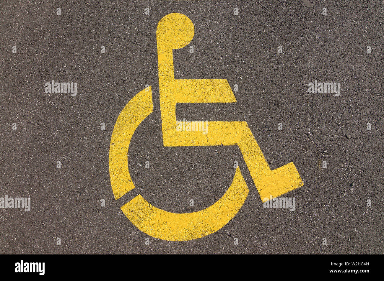 Close up picture of yellow disable handicap parking sign drawn on the asphalt of a street in Caslano, Ticino - Switzerland Stock Photo