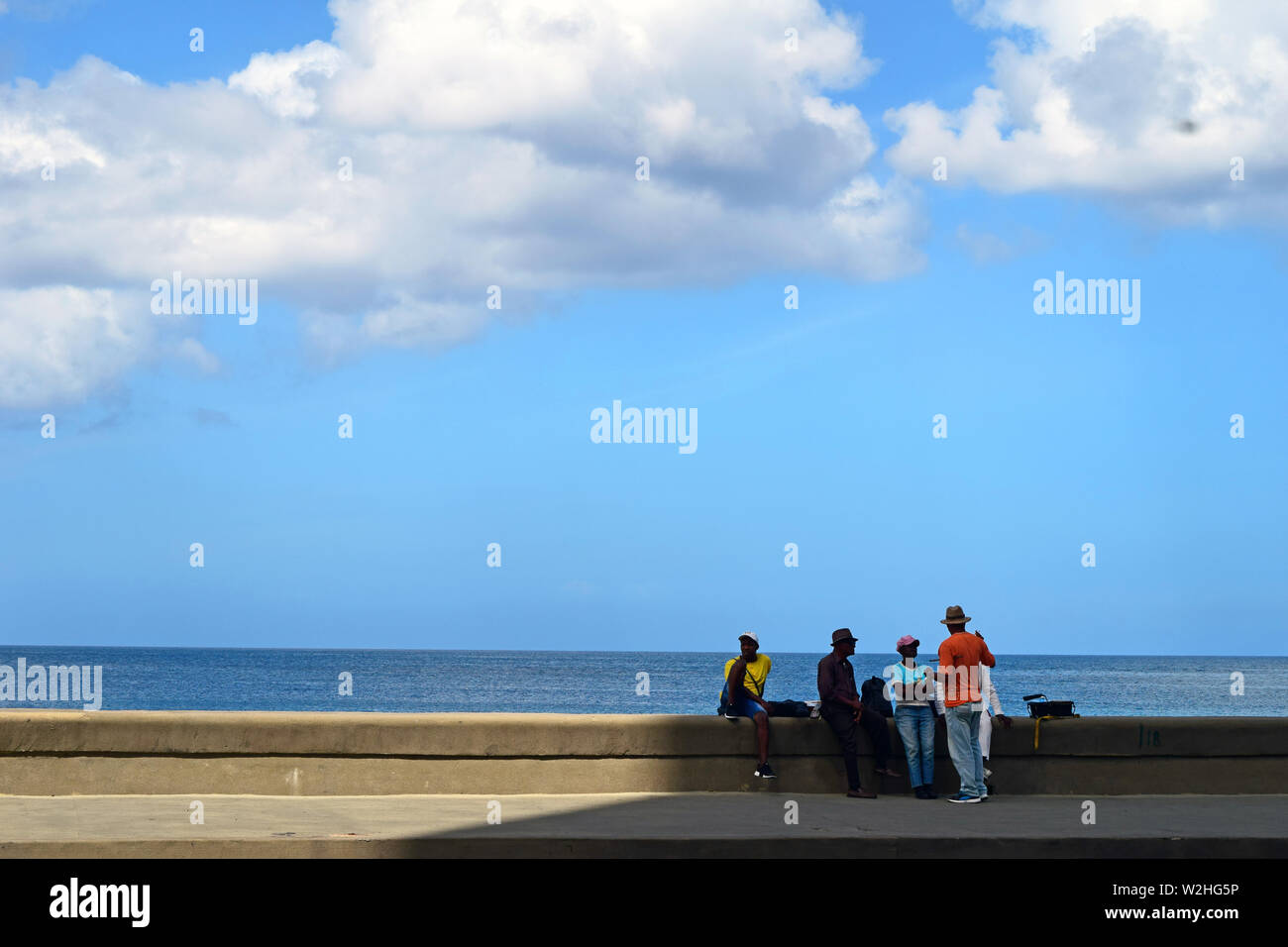 Cuba, Havana, February 10, 2018: a typical day in one of the streets of Havana, when people take a break seated against seascape Stock Photo