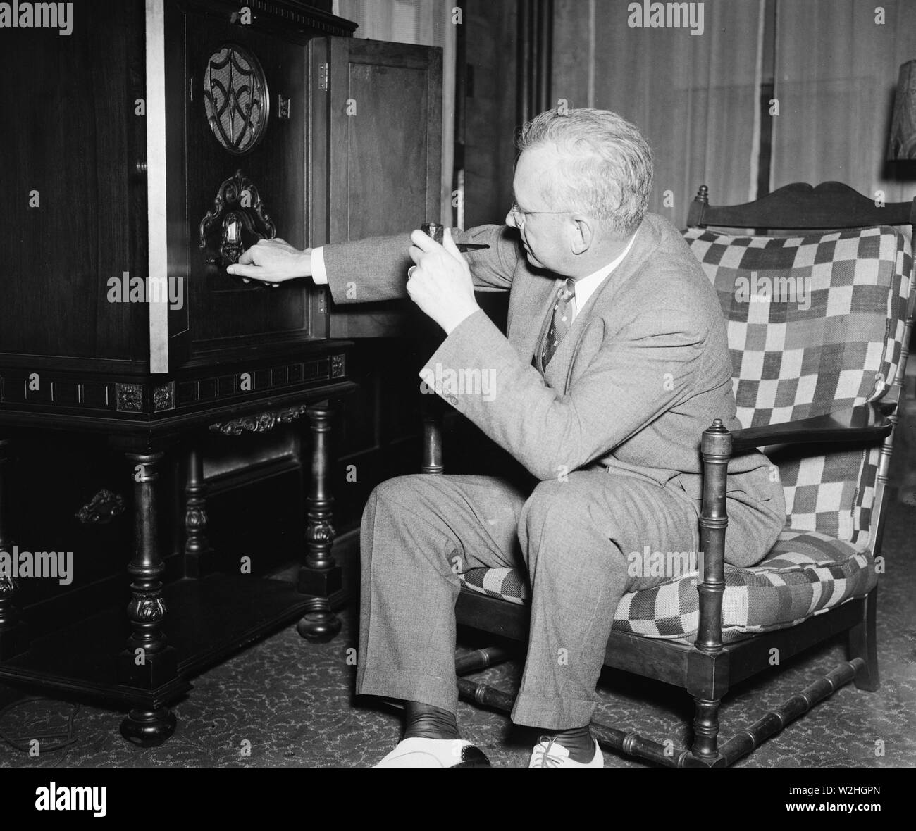 Man sitting in chair listening to a radio and tuning the radio ca. 1936  Stock Photo - Alamy