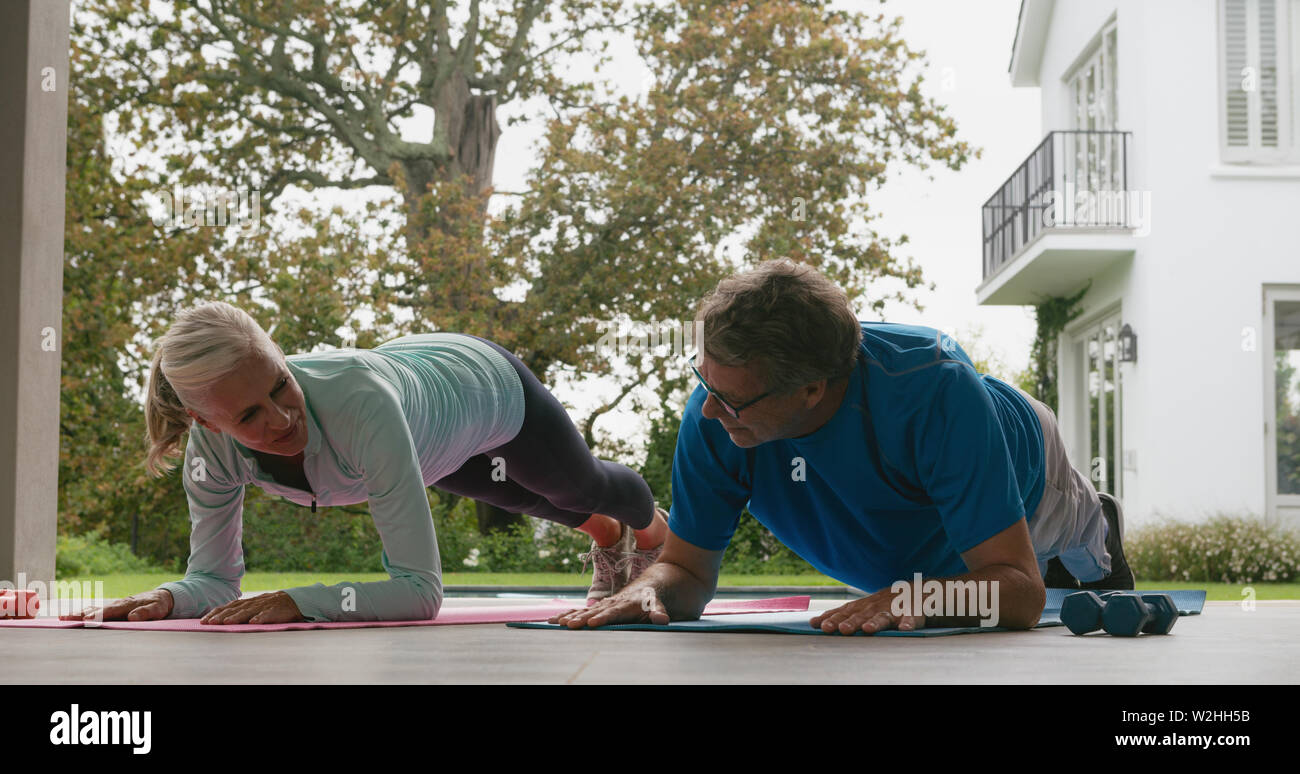Active senior couple doing plank exercise in the porch at home Stock Photo