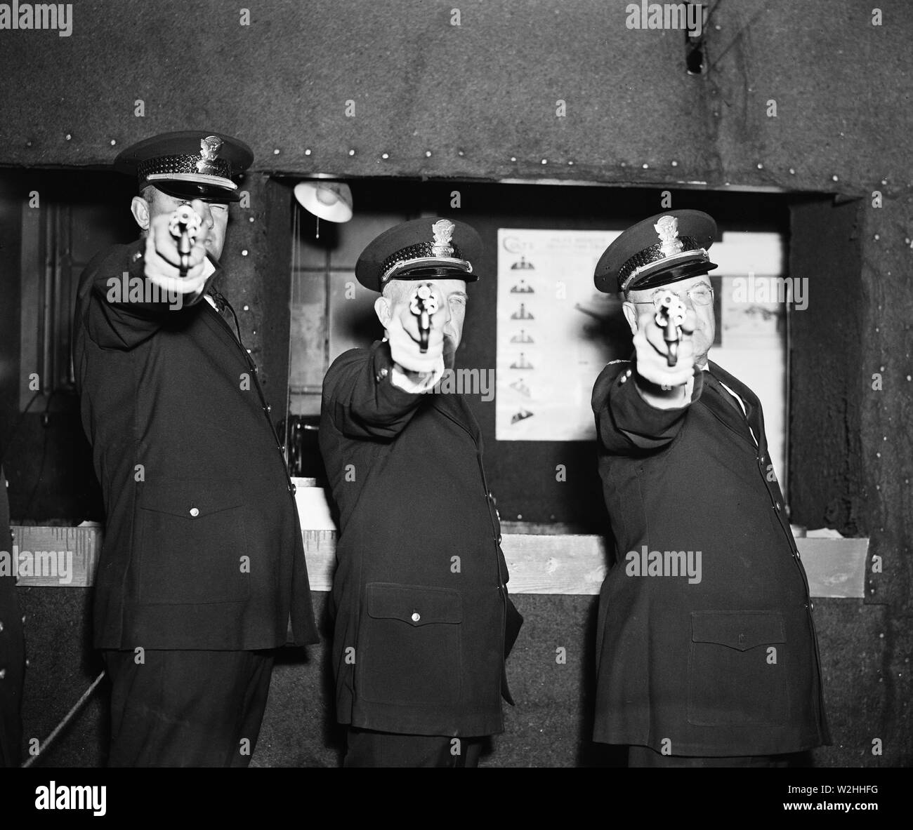 Three police officers pointing their guns (revolvers) at the photographer ca. 1936 Stock Photo
