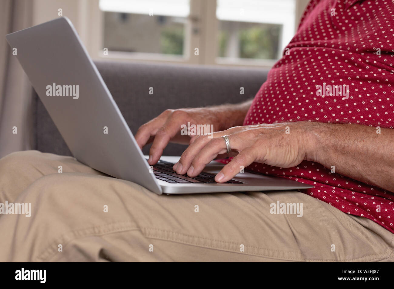 Active senior man using laptop on sofa in a comfortable home Stock Photo