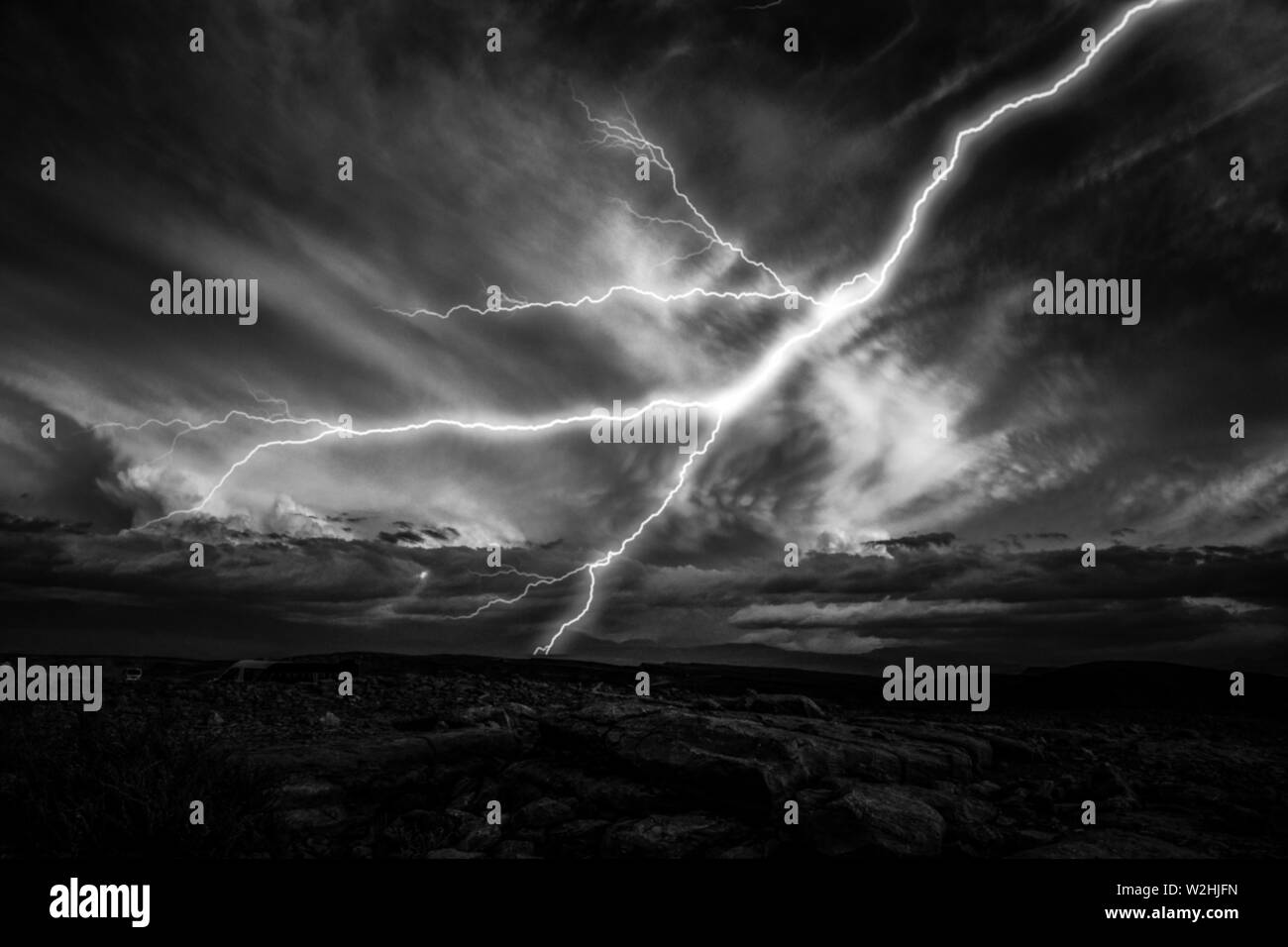 Lightnings striking towards the ground. Lightnings during a thunderstorm at night. Black and white image Stock Photo