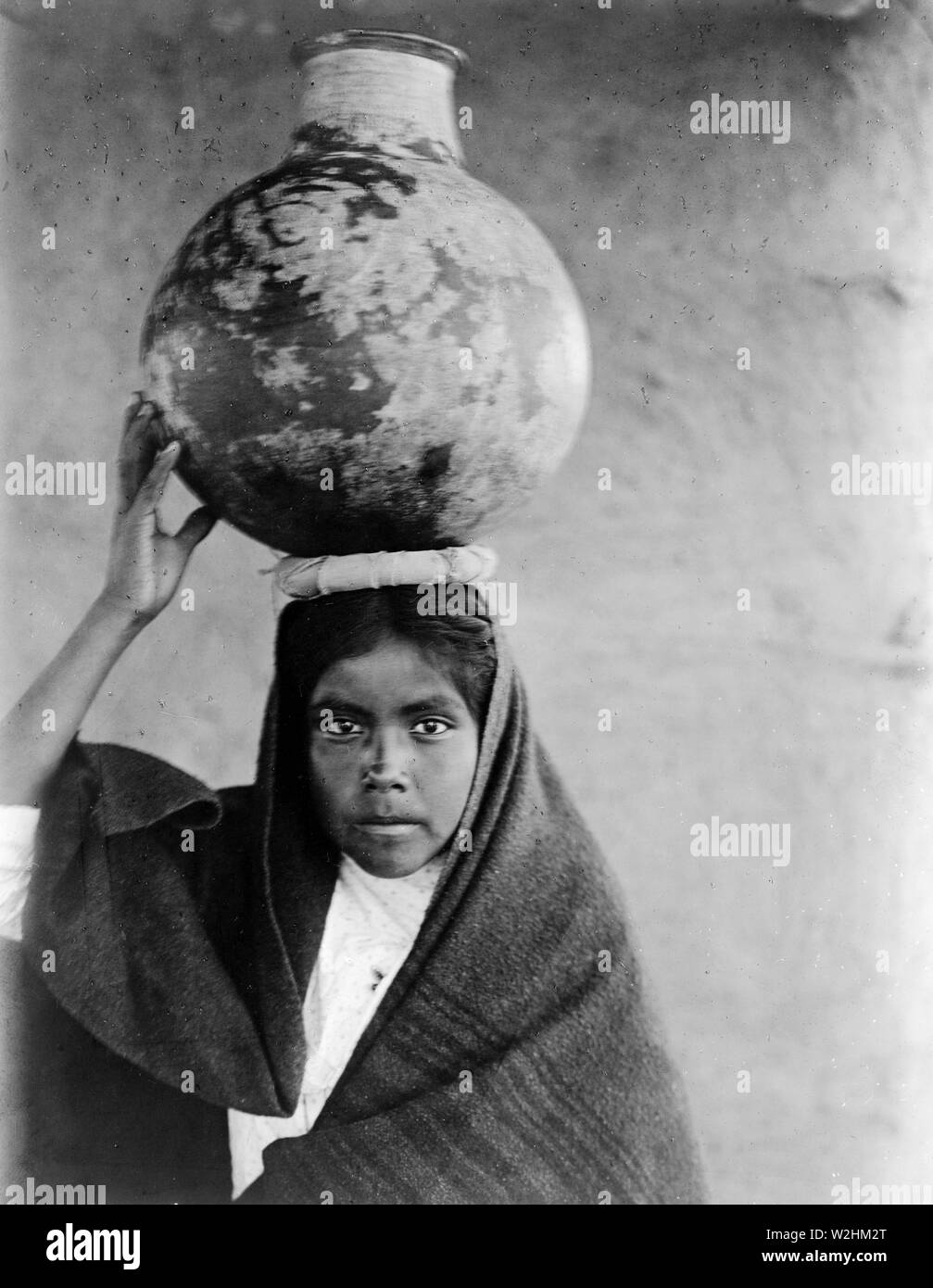Photograph shows a girl balancing a water jug on her head Stock Photo