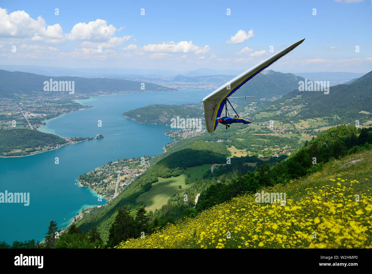 2014-06-25 Annecy, France. Hang glider pilot do aerobatic maneuvers over lake Annecy. Popular place for doing extreme sports. Stock Photo