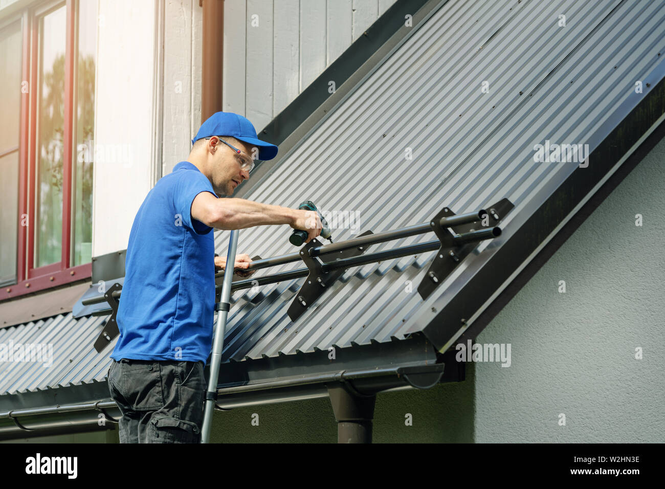 roofer installing snow guard on metal roof Stock Photo