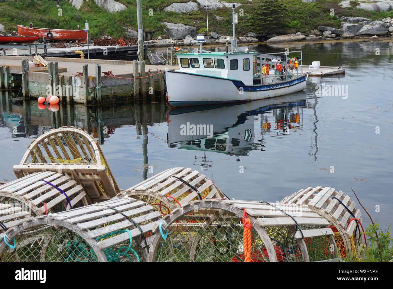 Wooden lobster traps and a fishing boat in Peggy's Cove, Nova Scotia Stock Photo