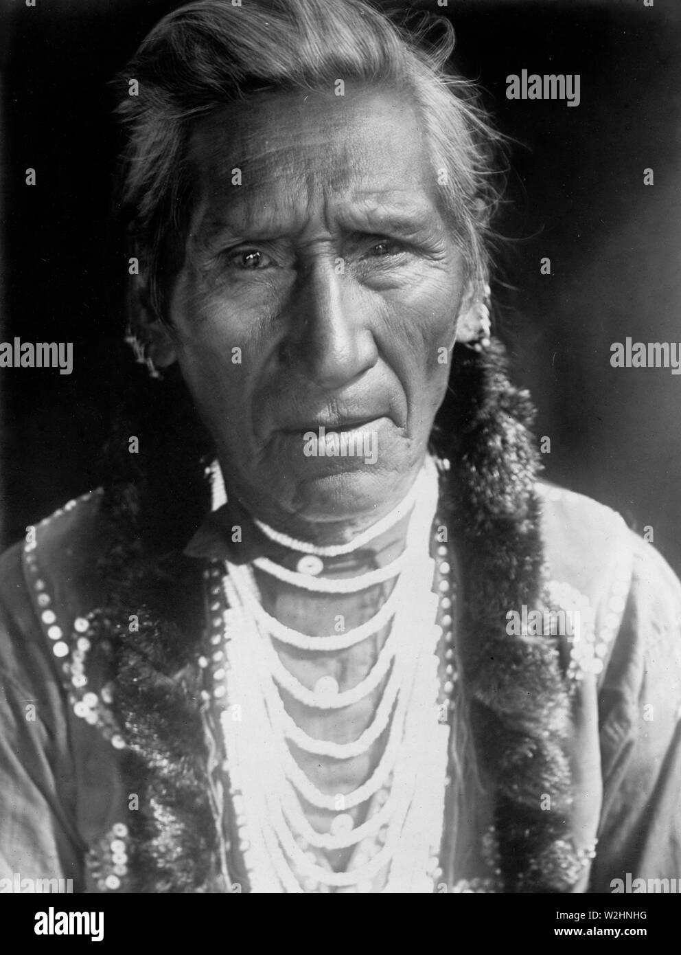 Edward S. Curits Native American Indians - Photograph shows Flathead man, head-and-shoulders portrait, facing front ca. 1910 Stock Photo