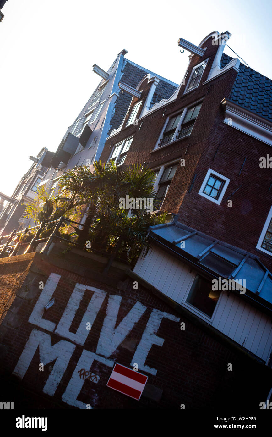 Love Me printed onto the side of a building in Amsterdam during sunset Stock Photo