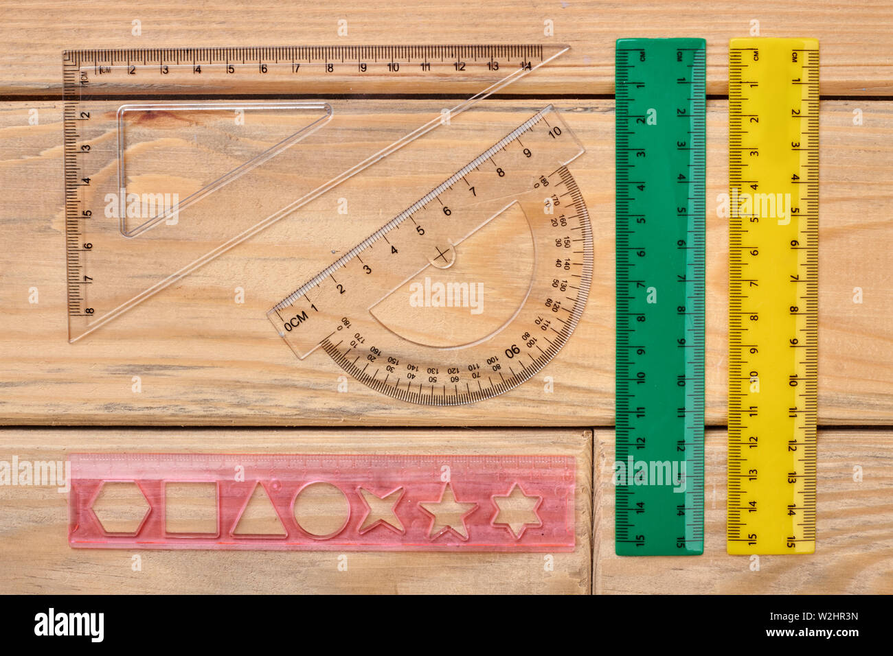 Various plastic rulers on wooden background. Stock Photo