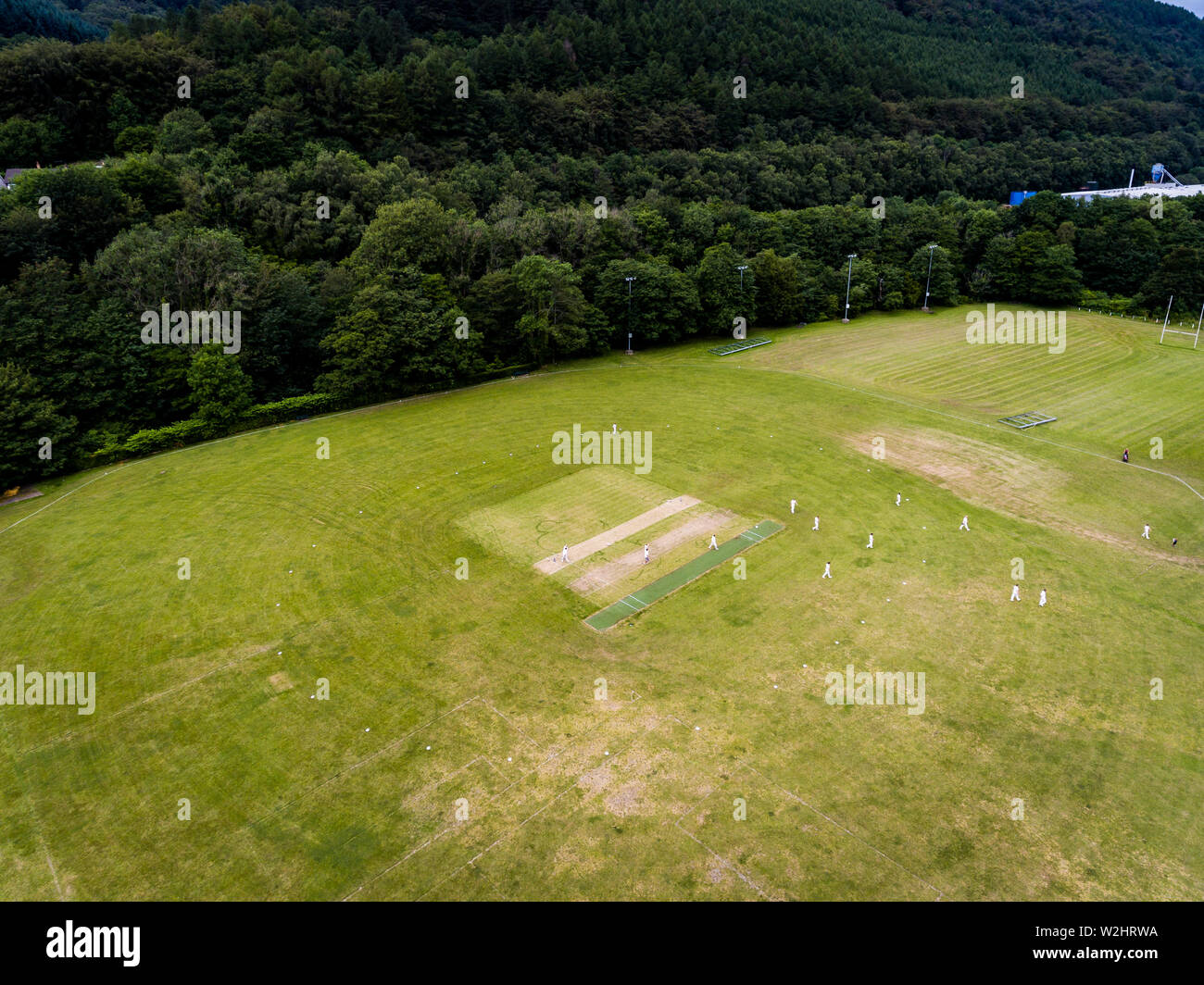 Aerial view of players, playing a game of Cricket on a Welsh Park Pitch in the summer Stock Photo