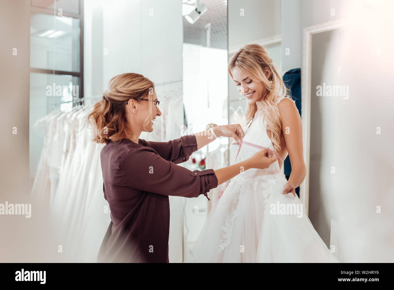 Tailor taking measures of a young woman. Stock Photo