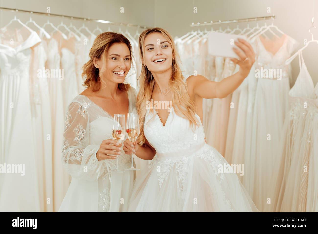 Two happy women taking selfies in wedding dresses. Stock Photo