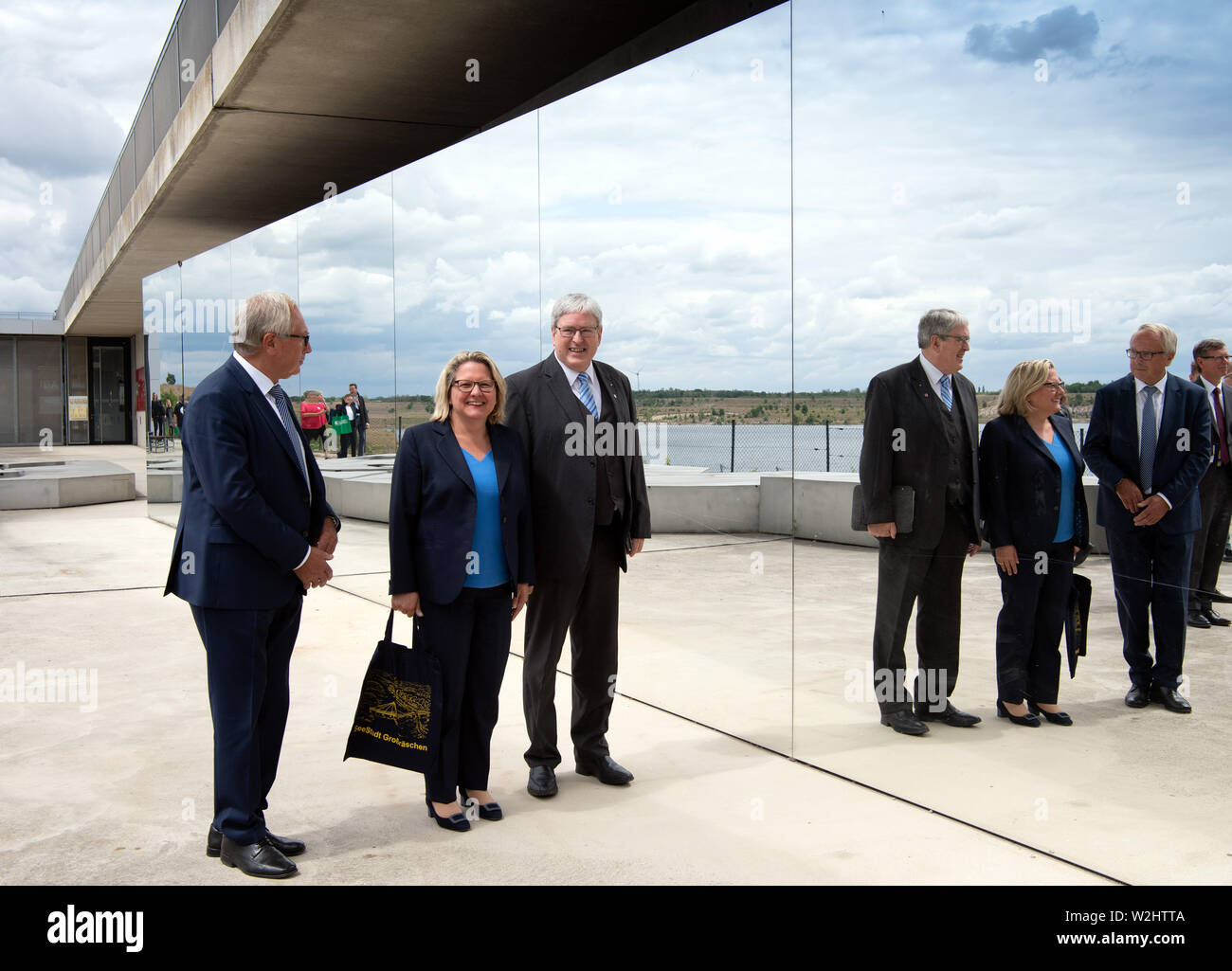 09 July 2019, Brandenburg, Großräschen: Svenja Schulze, Minister for the Environment, Nature Conservation and Nuclear Safety, and Jörg Steinbach (both SPD), Minister of Economic Affairs in Brandenburg, will visit the Großräschener See from the terraces of the Lusatian Lakeland Visitor Centre under the leadership of Klaus Zschiedrich (l), Managing Director of the Lausitzer und Mitteldeutsche Bergbau-Verwaltungsgesellschaft (LMBV). The artificial lake was created by flooding the Meuro brown coal open-cast mine in 2007. The vineyards on the Großräschen lake shores are the only steep slopes in Bra Stock Photo