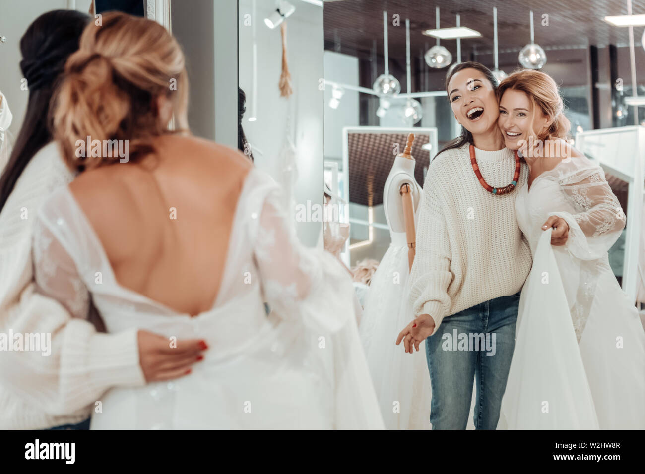 Two happy women hugging in front of the mirror. Stock Photo