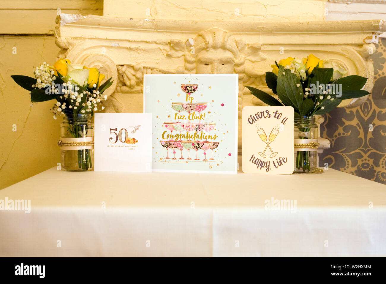 Display table with jars of flowers and greeting cards at a party celebrating a a couple's golden wedding Stock Photo