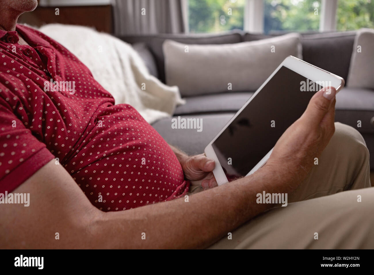 Active senior man using digital tablet on sofa in a comfortable home Stock Photo