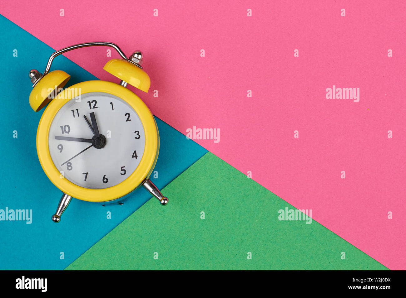 Yellow alarm clock on multicolored background Stock Photo - Alamy