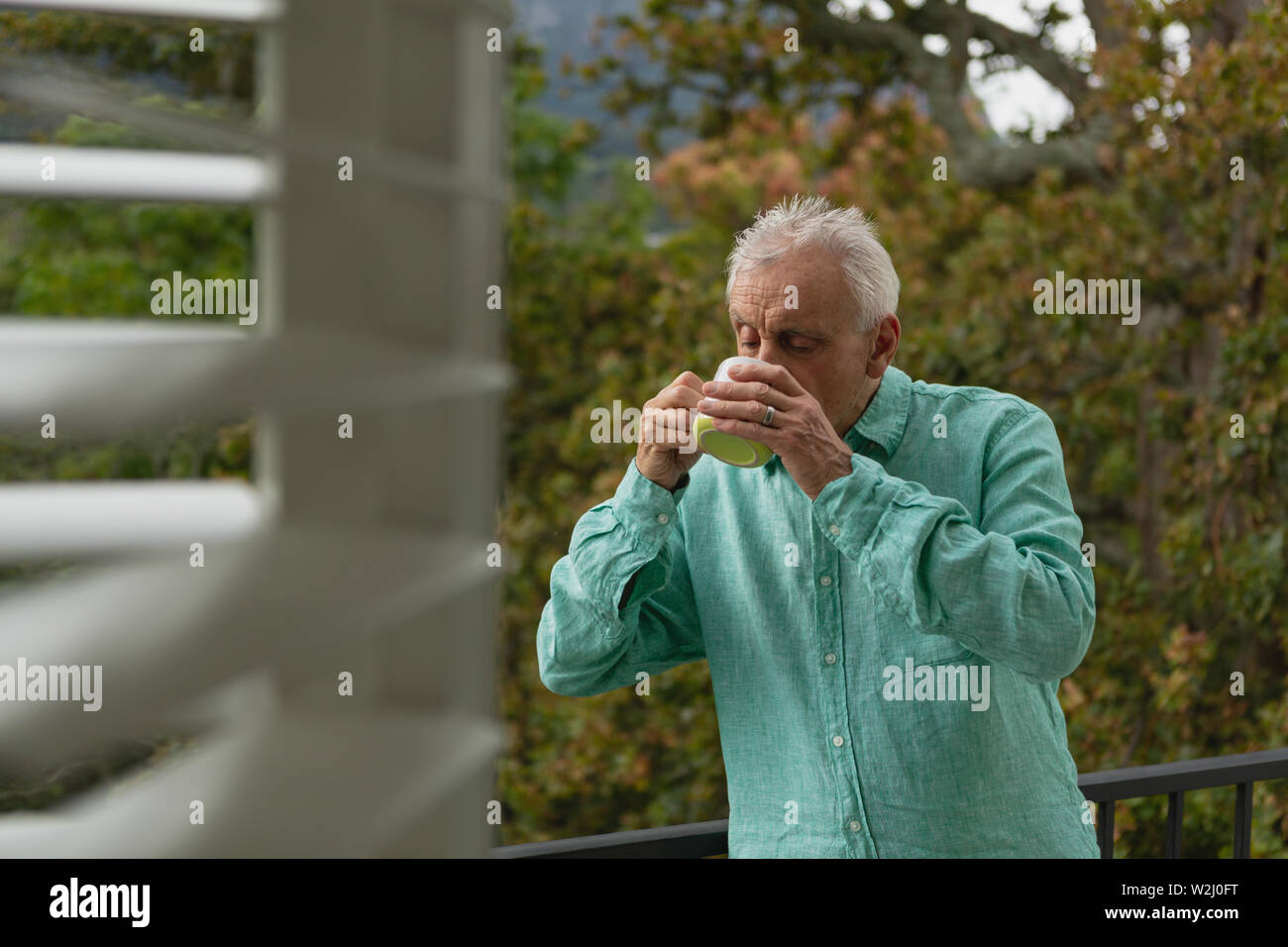 Active senior man drinking coffee on the balcony Stock Photo