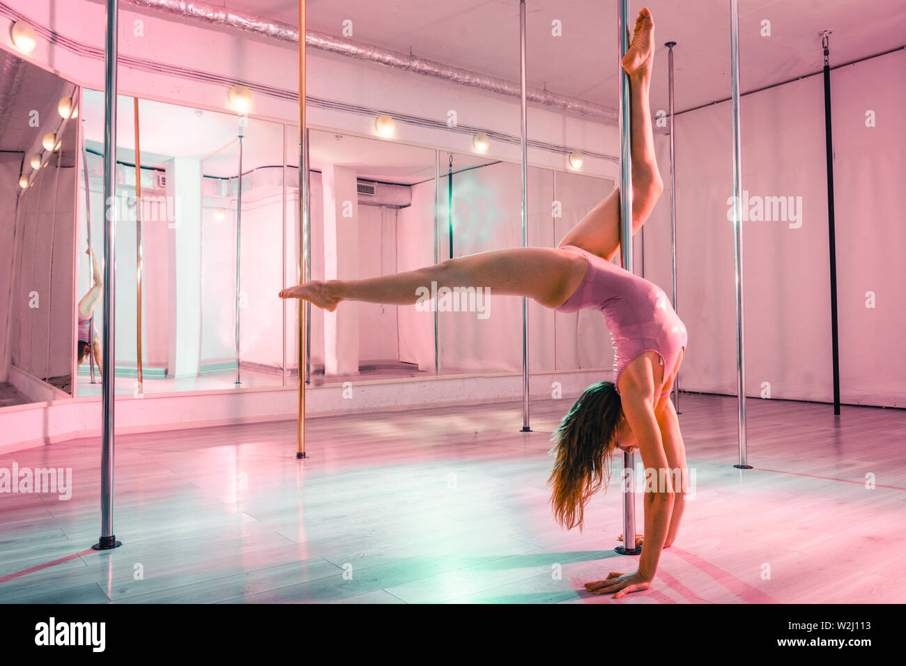 Dancer standing on her hands near the pole. Stock Photo