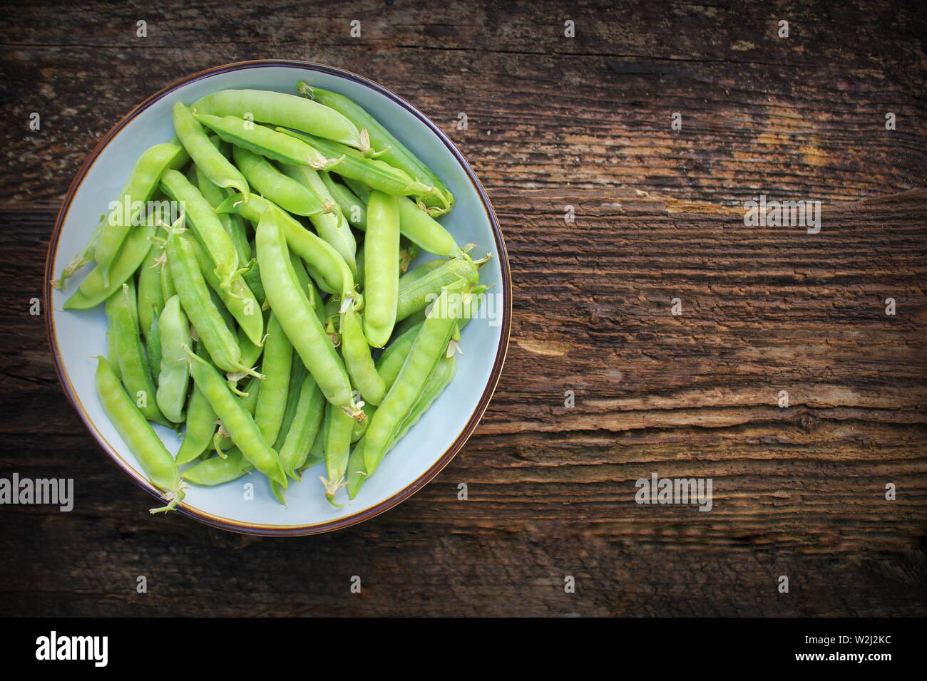 Green peas in bowl on wooden table background. Top view Stock Photo