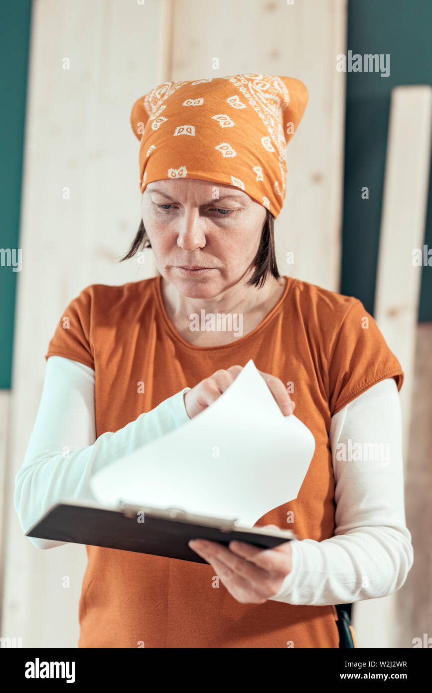Female carpenter reading DIY project notes in small business woodwork workshop Stock Photo