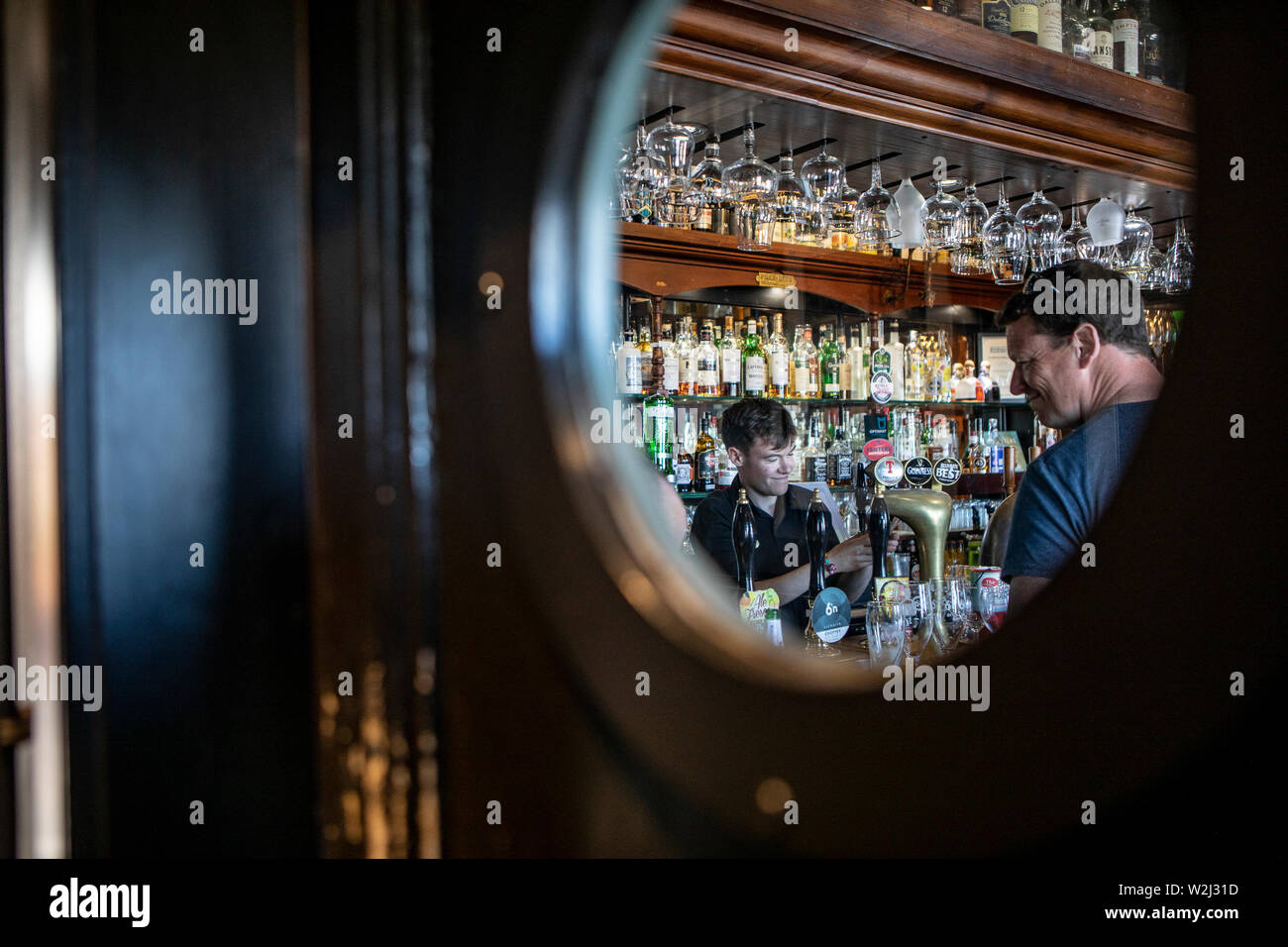 pub entrance  with a peephole, trough you see a bartender handling with drafts beer Stock Photo