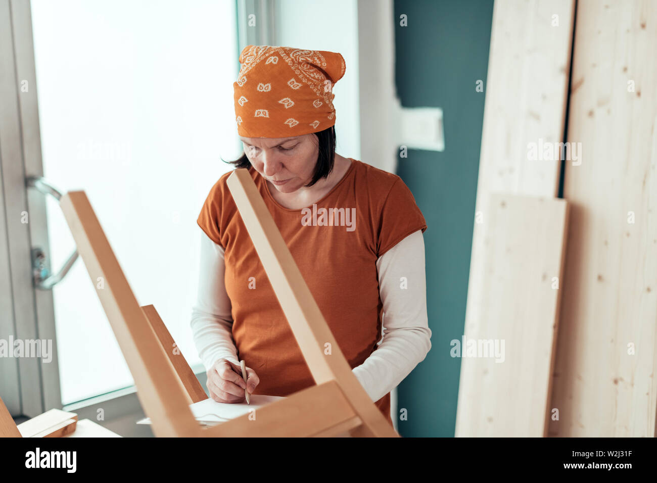 Female carpenter repairing wooden chair seat in small business woodwork workshop Stock Photo