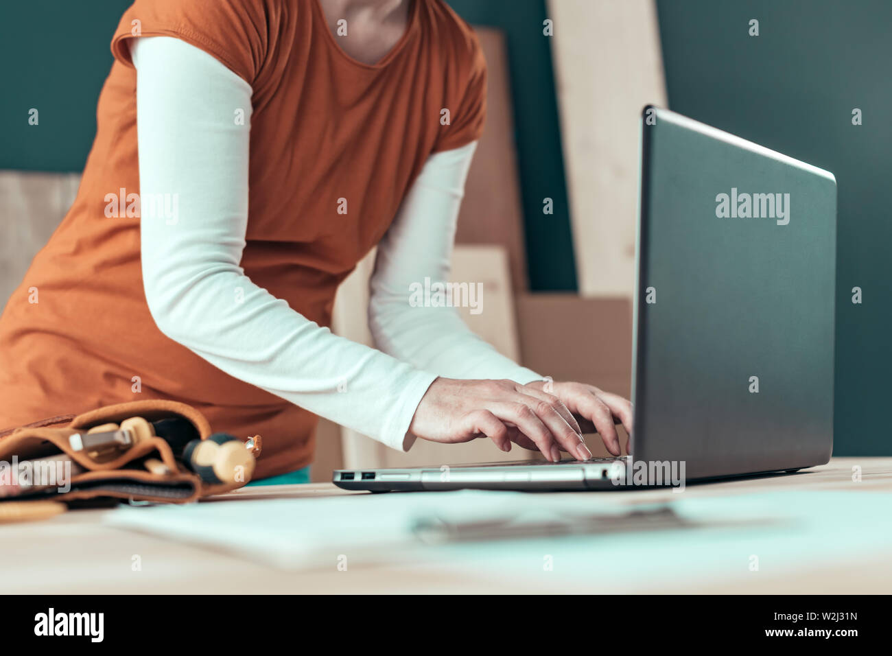 Female carpenter typing laptop computer keyboard in woodwork workshop Stock Photo