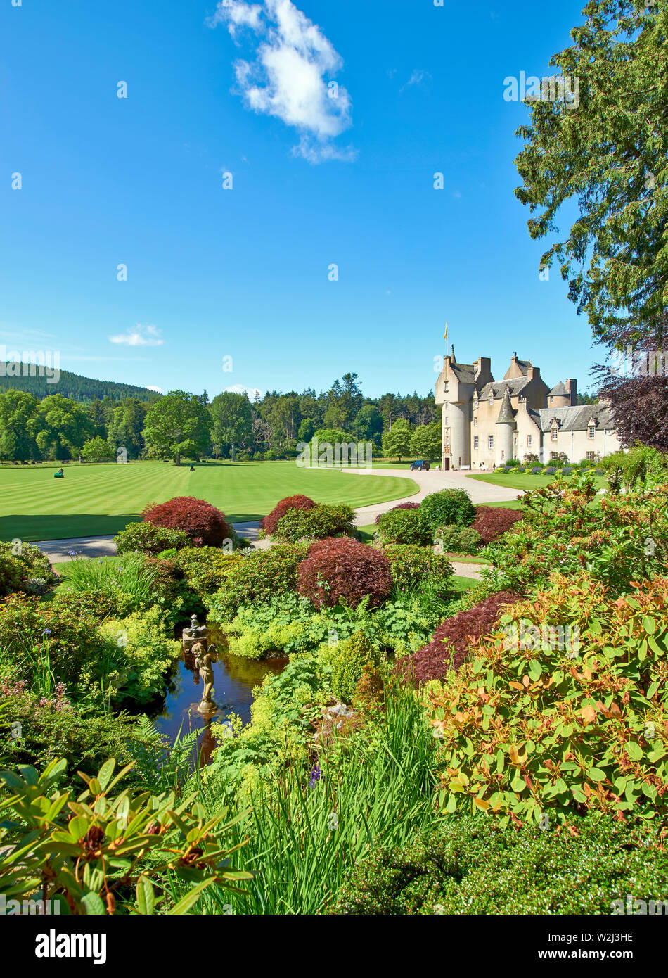 BALLINDALLOCH CASTLE AND GARDENS BANFFSHIRE SCOTLAND THE POND AND MEN MOWING THE LAWNS Stock Photo