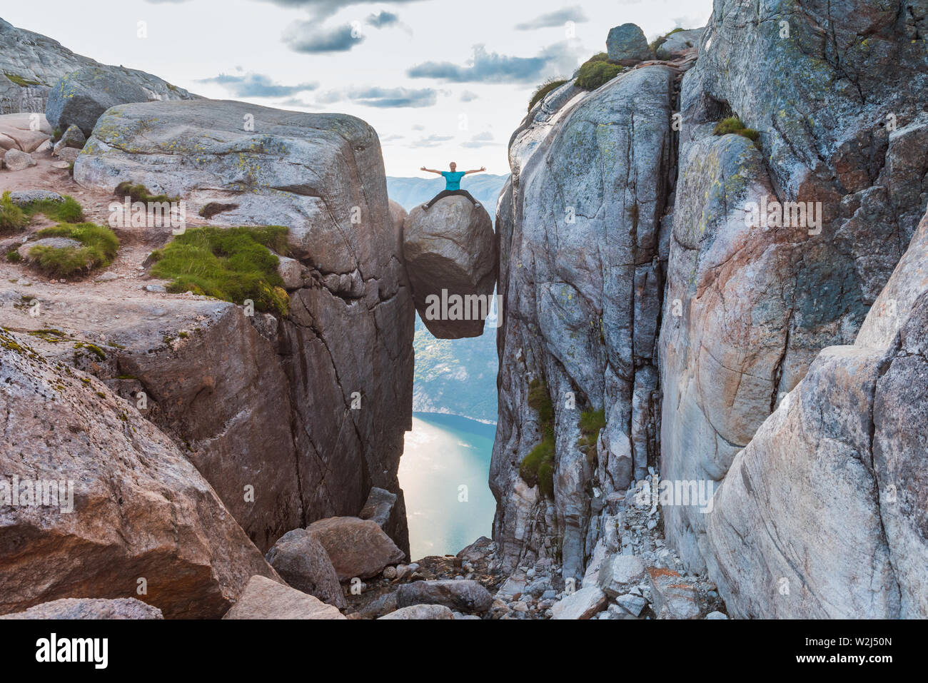 Woman on Kjeragbolten Travel in Norway Kjerag mountains, extreme vacations, adventure, tourist, happy emotions, success concept Stock Photo