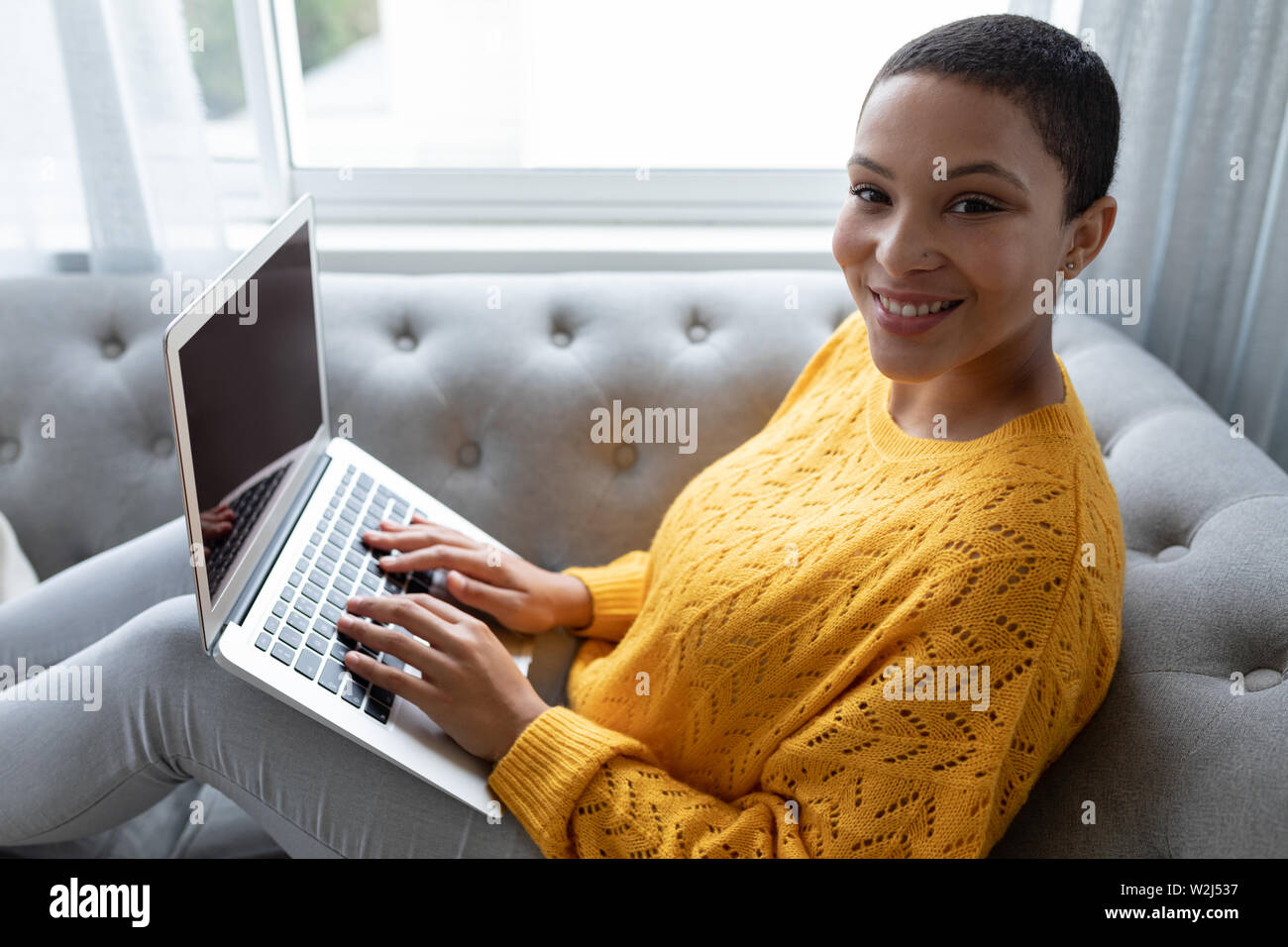 Woman using laptop on a sofa in living room at home Stock Photo - Alamy