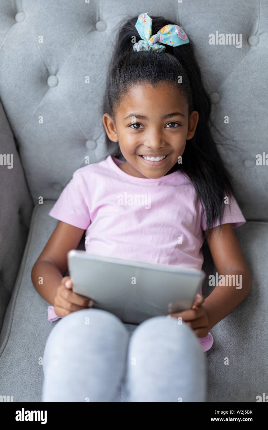 Girl using digital tablet on a sofa in living room Stock Photo