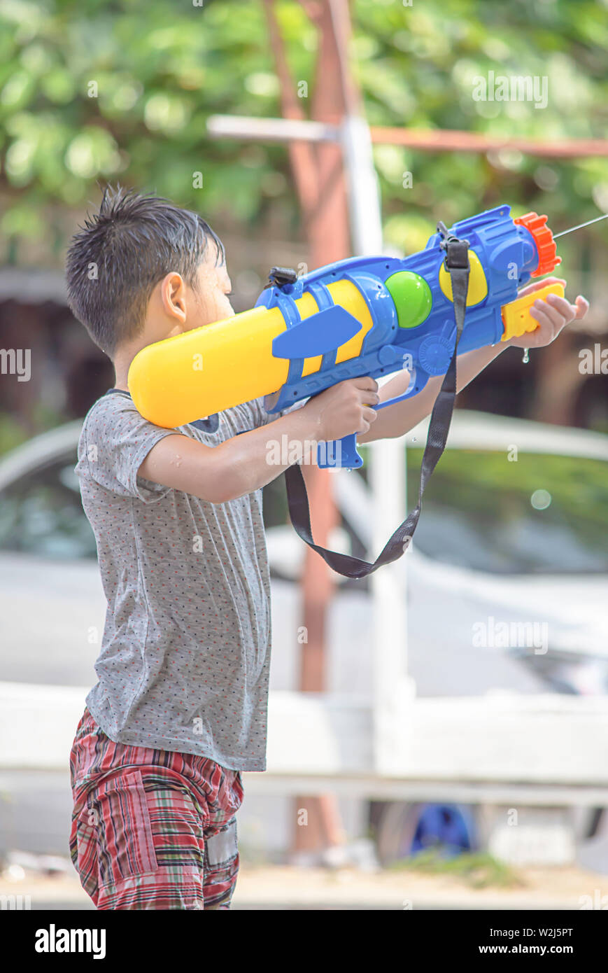 Asian boy holding a water gun play Songkran festival or Thai new year in Thailand. Stock Photo