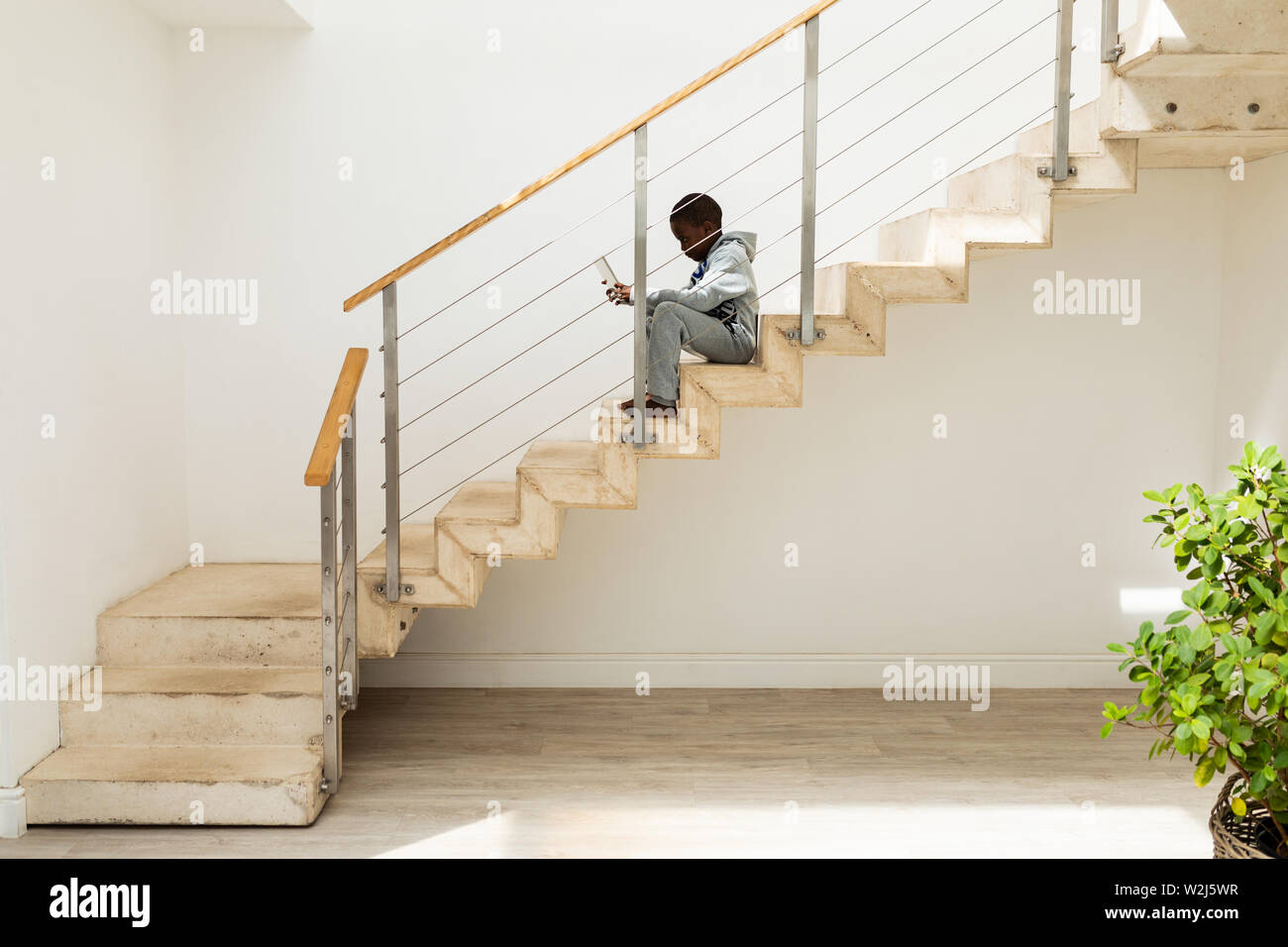 Boy using digital tablet on staircase at home Stock Photo