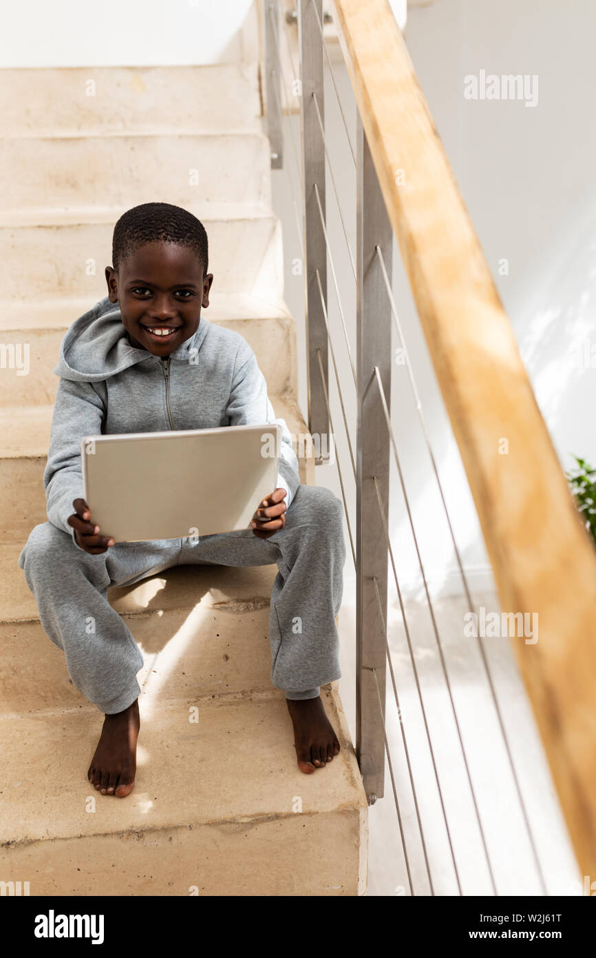 Boy using digital tablet on staircase at home Stock Photo