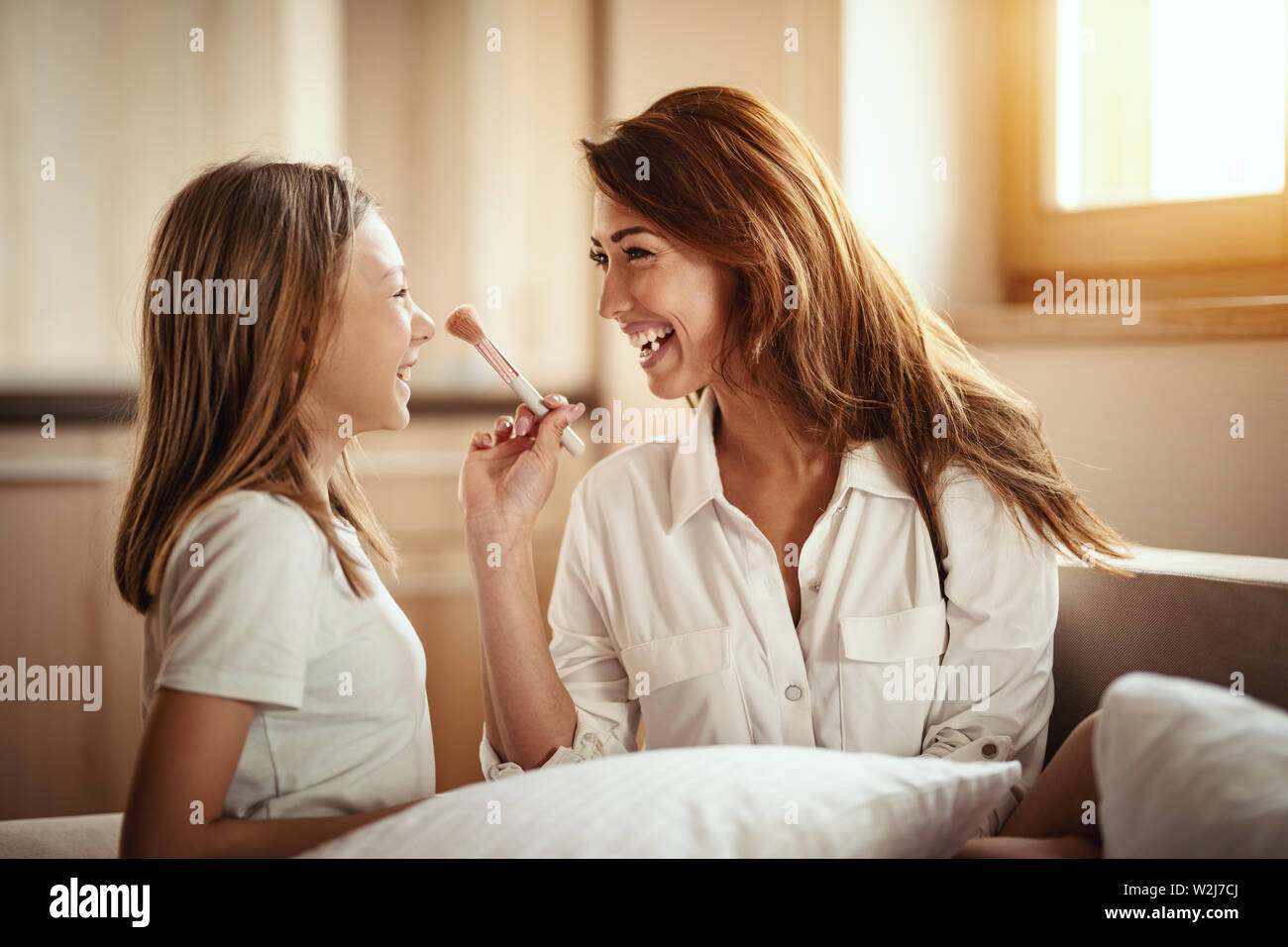 Little Daughter And Her Young Mother Are Having Fun Playing Beauty Salon And Mother Is Putting Makeup On Her Daughter S Face With Big Puffy Brush Stock Photo Alamy