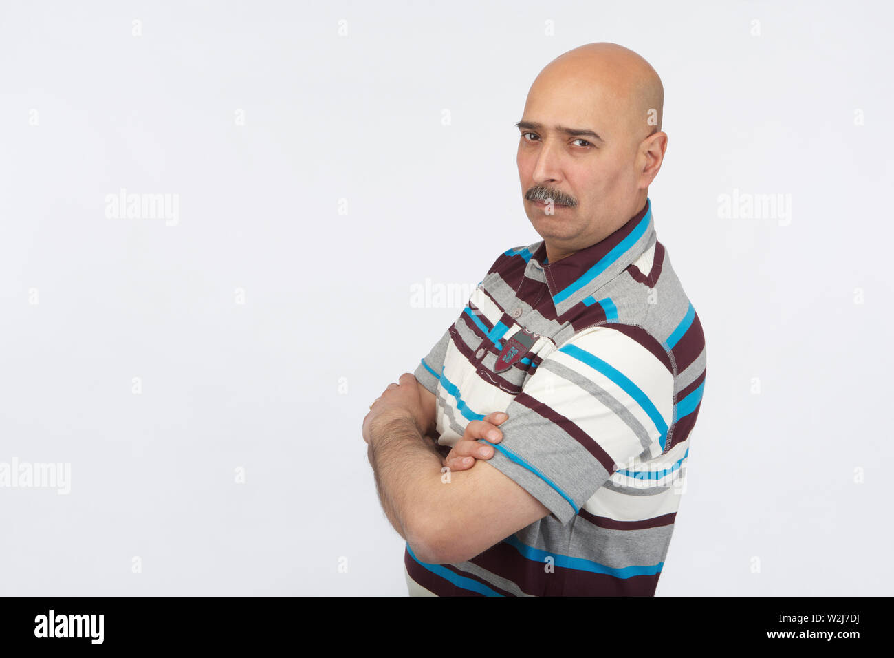 Portrait of an Indian bald man standing with his arms crossed Stock