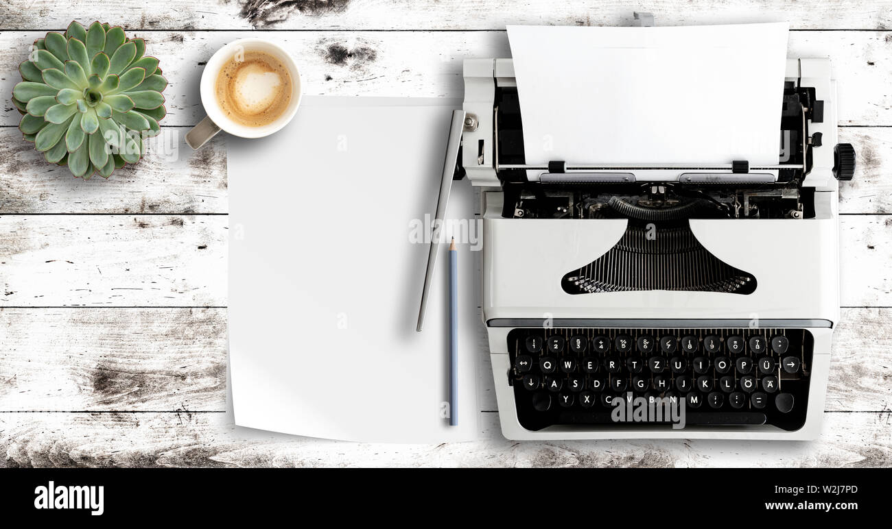 overhead shot of typewriter and paper on white wooden table Stock Photo