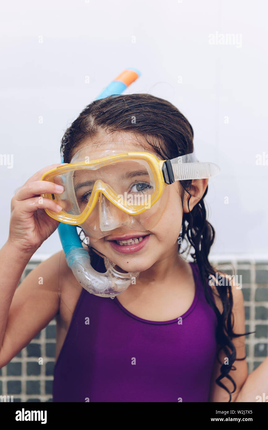 vertical portrait of a happy pretty little girl smiling with snorkel goggles in the tub while taking a bath in the bathtub, kids hygiene concept, copy Stock Photo