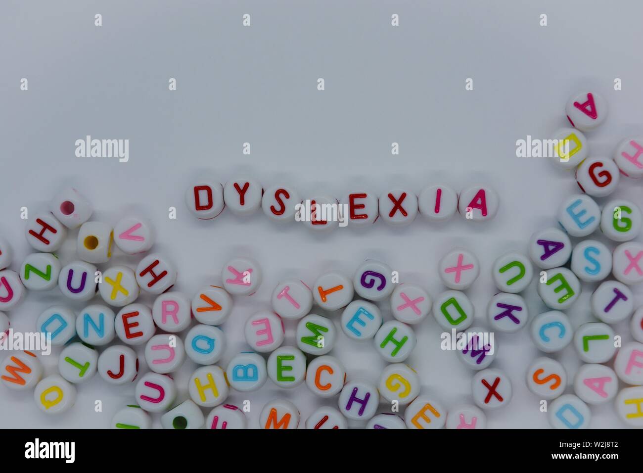Dyslexia, spelt out in red letters, surrounded by a sea of random letters, on white background with copy space.  Creative concept : reading disability Stock Photo