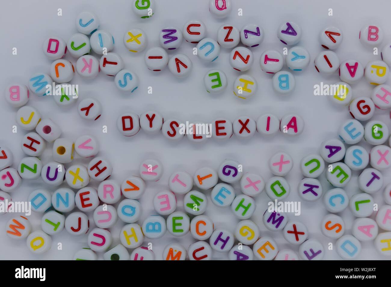 Dyslexia, spelt out in red letters, surrounded by a sea of random letters, on a white background. Creative concept : reading disability Stock Photo